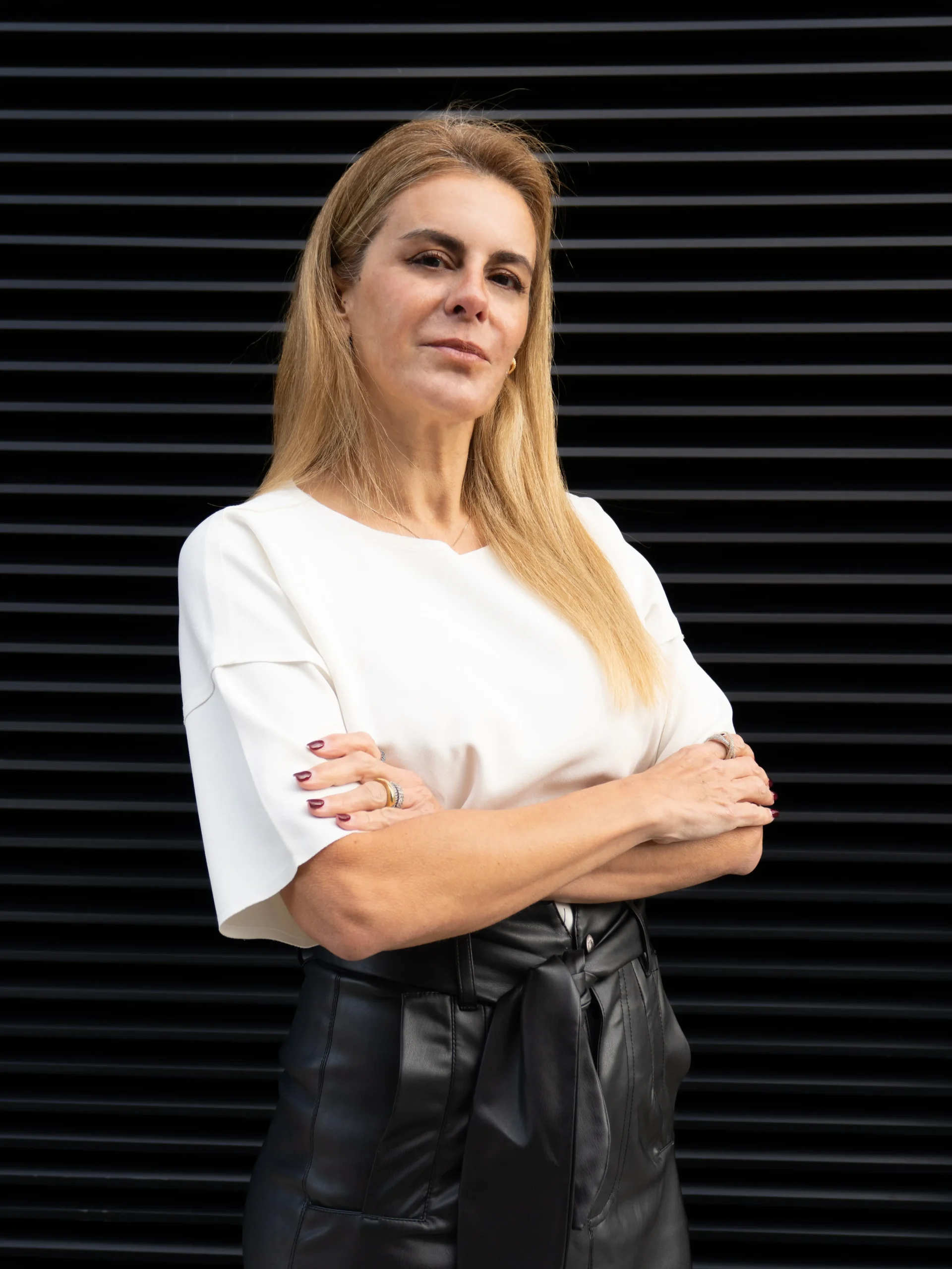 Fotografía de Maria Gloria Ficarrotta Páez co-founder de Arista, con remera blanca, cruzada de brazos, mirando hacia la cámara.